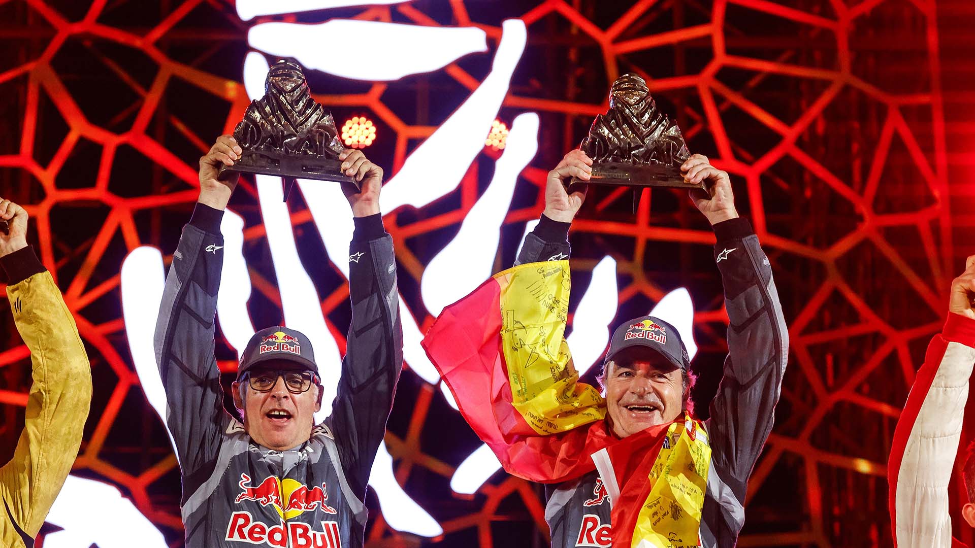 Das Foto zeigt Carlos Sainz und Lucas Cruz, die ihren Sieg bei der Rallye Dakar 2024 feiern.
