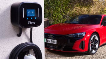 An Ohme charge point on a wall with a parked red Audi electric vehicle in the background 