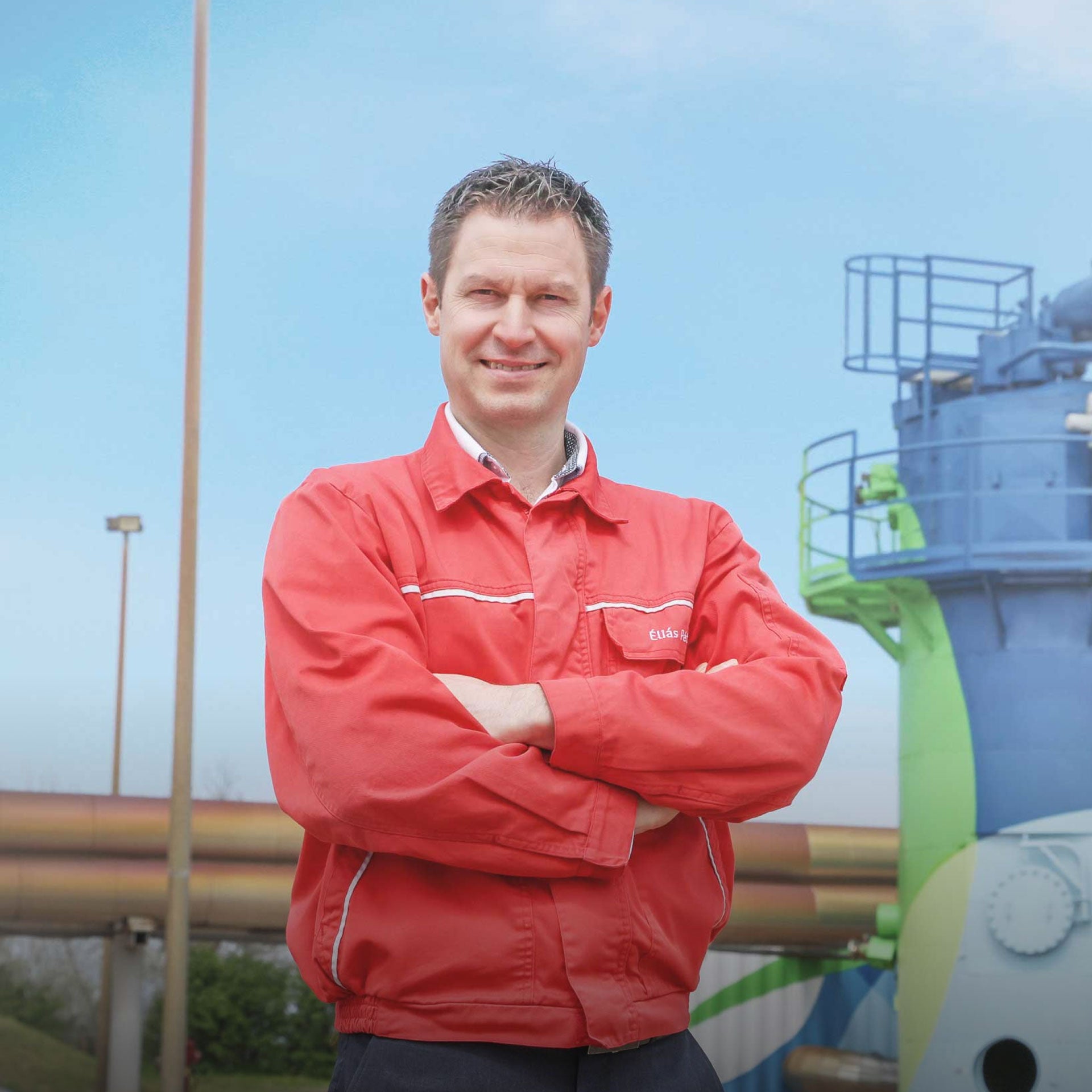 Porträt von Peter Elias, Leiter Umweltmanagement Audi Hungaria, in roter Arbeitskleidung vor Industrieanlage im Freien.