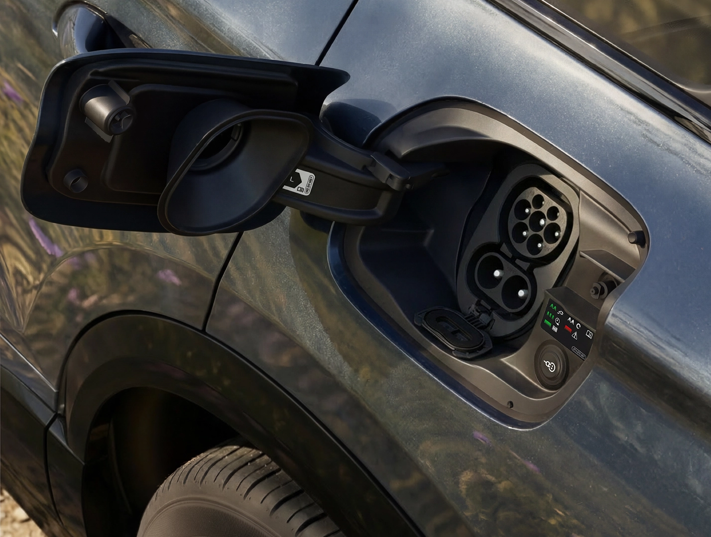 Close-up of the charging socket on the Q6 SUV e-tron, into which a man is plugging a charging cable.