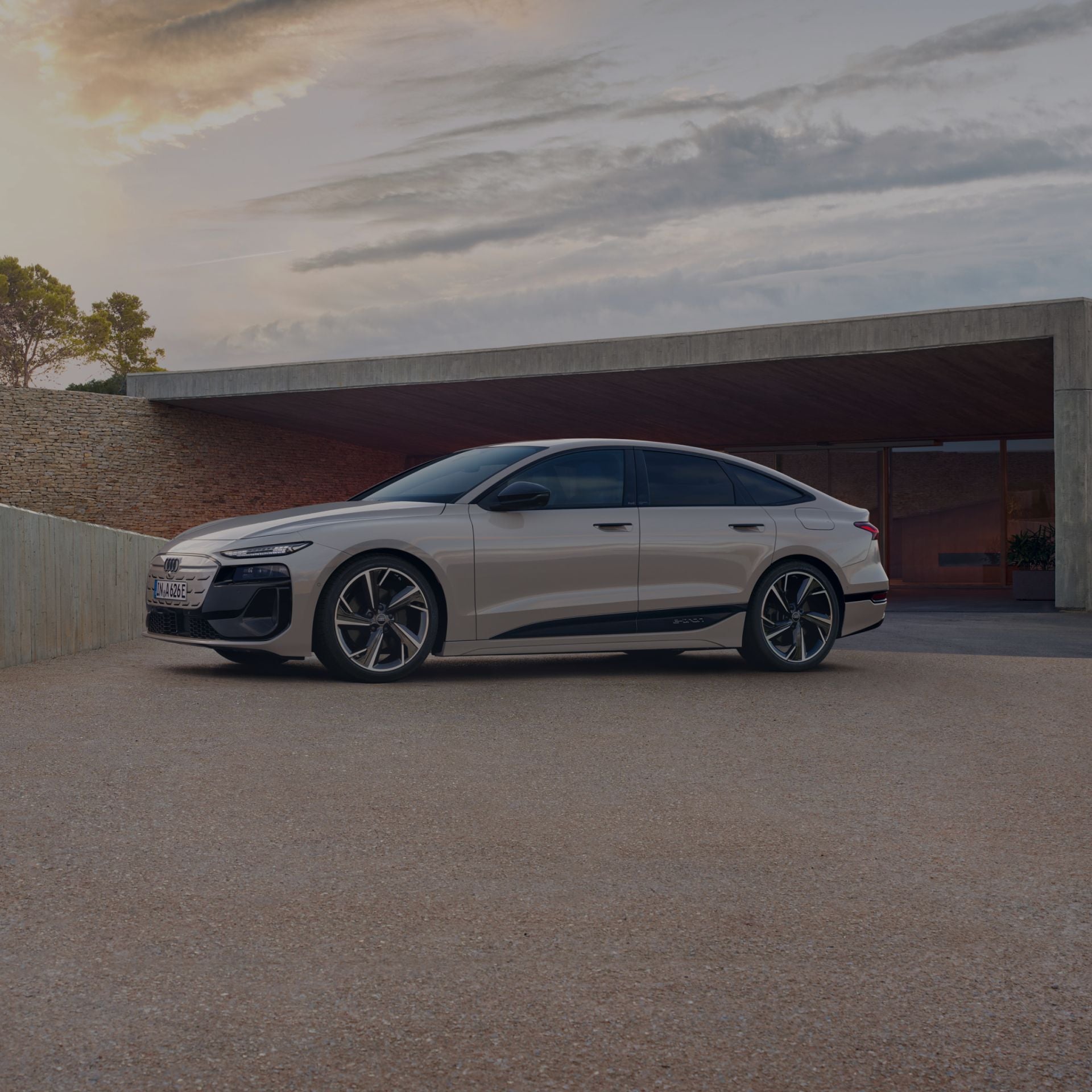 Sedan parked in front of a modern building at dusk.