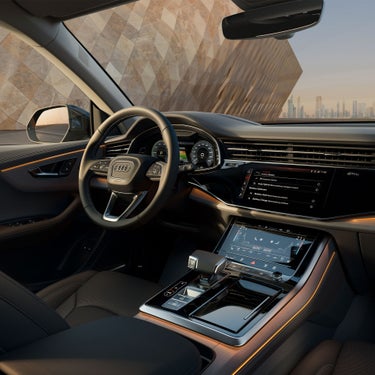 Innenraum eines Audi Q8 SUV TFSI e mit digitalem Cockpit, zwei Touchscreens und ambienter Beleuchtung.