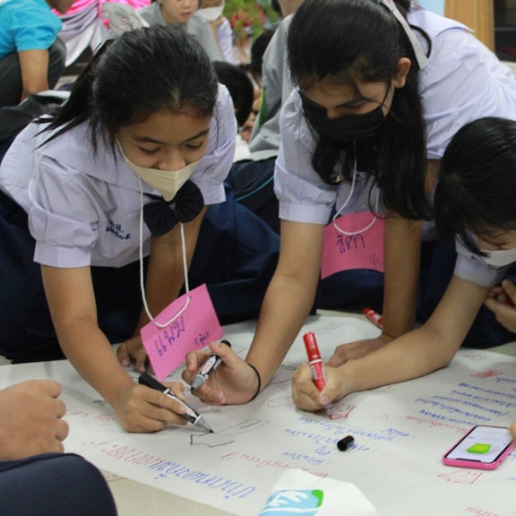 Schulkinder malen ein Plakat.