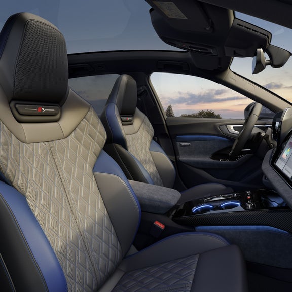 Innenansicht eines Audi A5 Avant mit zwei Sportsitzen, digitalem Display und blauen Kontrastelementen.