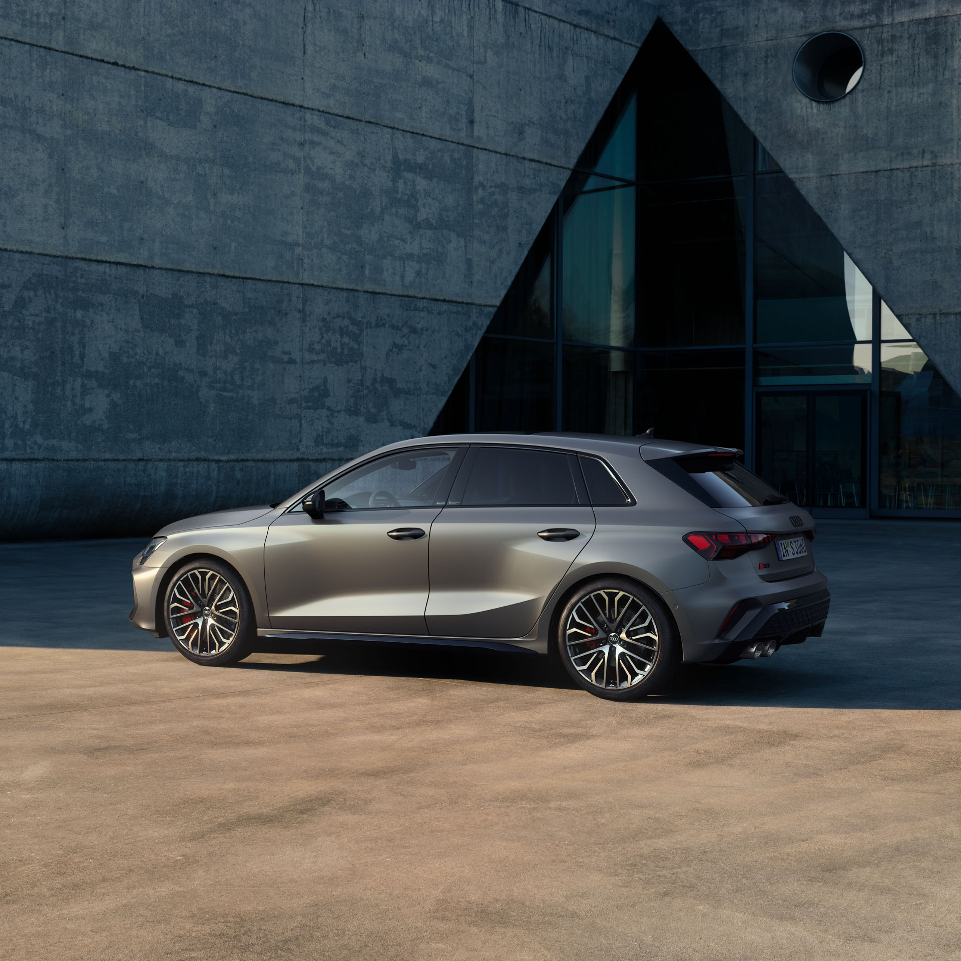 Silberner Audi S3 Sportback vor modernem Gebäude bei Tageslicht seitlich fotografiert.