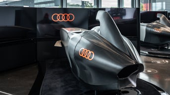 Ein Audi racing Simulator steht im Vordergrund, ein zweiter dahinter auf einer runden Plattform.