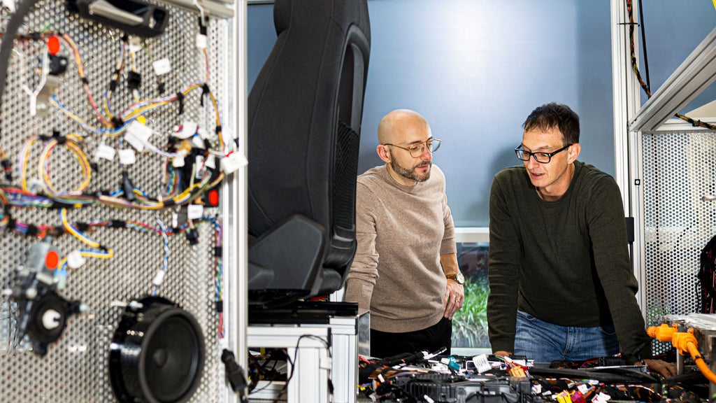 Mario steht mit einem Kollegen in einer Werkstatt