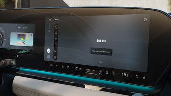 The central infotainment display in an Audi shows voice output settings and music player.