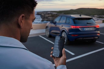 A female hand holding a phone with an Audi all launched