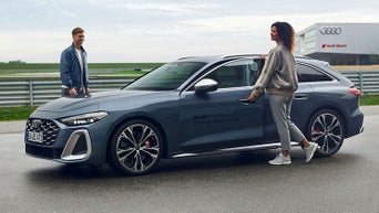 女性がAudiドライビングエクスペリエンスの車両に乗り込む様子。助手席側にインストラクターが立っています。