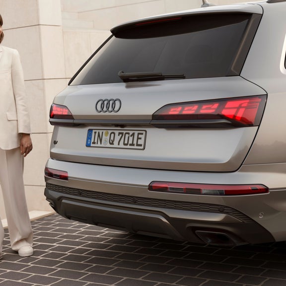 Person standing next to an Audi SUV.