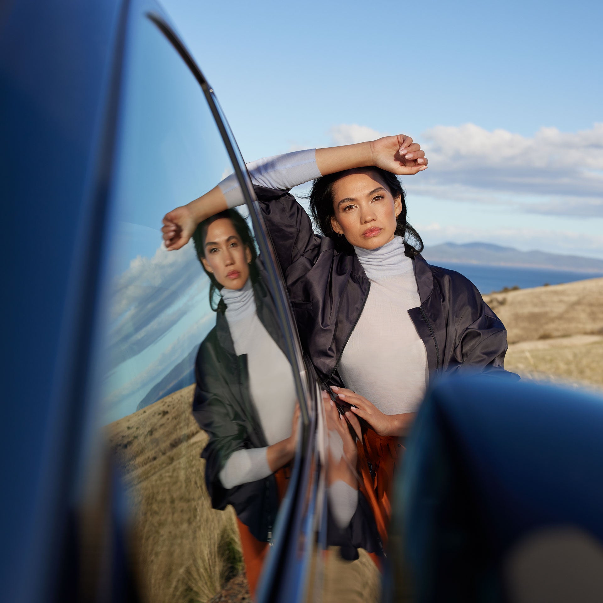 Eine Frau lehnt an einem Audi e-tron und spiegelt sich in der Scheibe.