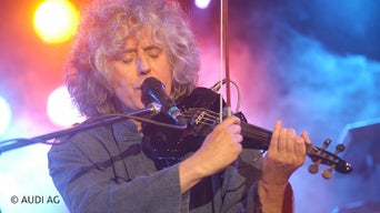 Mann spielt Geige und singt ins Mikrofon