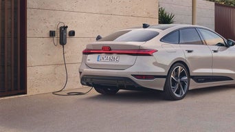 Audi A6 Sportback e-tron parked by a wall, connected to an EV charging station in a modern setting.