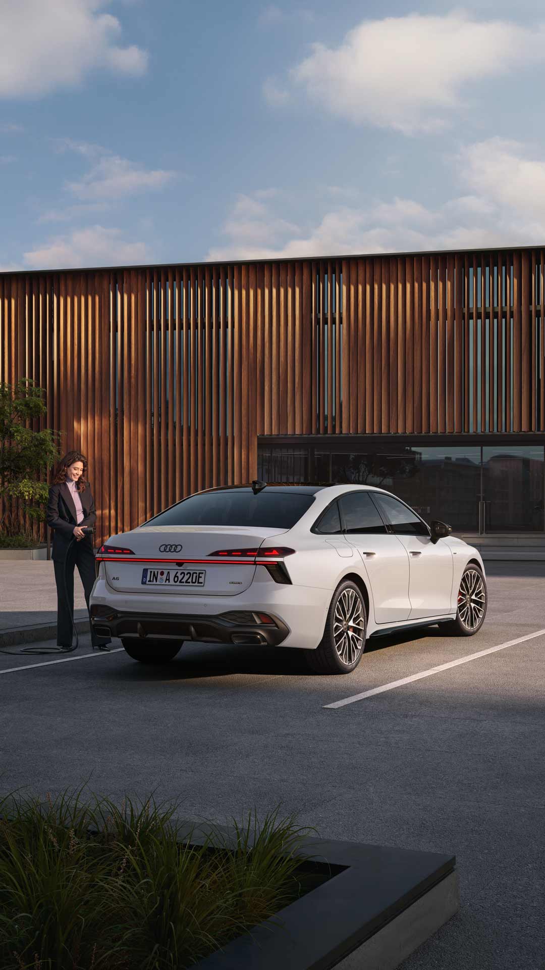Audi A6 sedan rear view with a woman standing next to the car