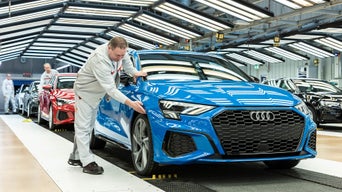 An employee checks a blue Audi in the final production inspection.