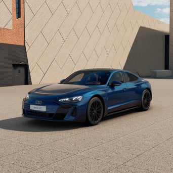 Ein blauer Audi e-tron GT quattro von schräg vorne fotografiert vor einer modernen Kulisse.