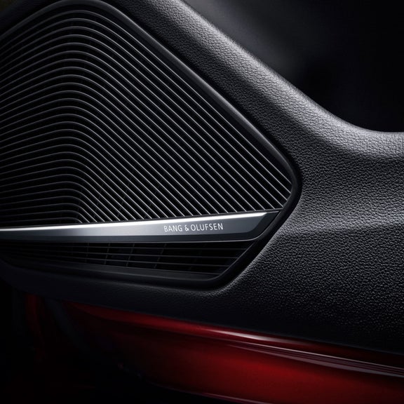 Close-up of a Bang & Olufsen speaker grille in a car door with textured details.