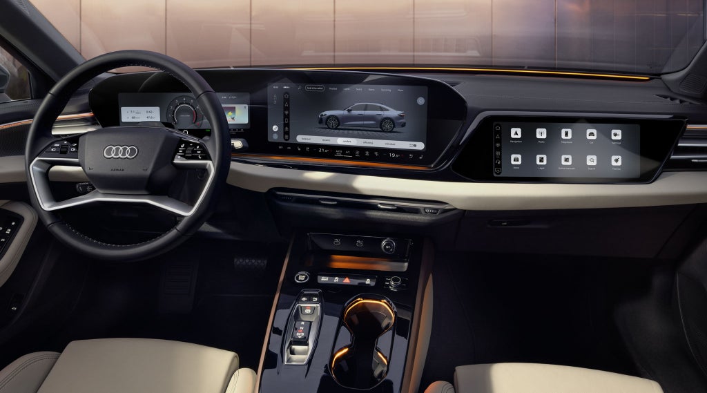View from the rear seat into the cockpit of the A5 Saloon. Visible features include the MMI displays and the lighting design, featuring the interaction light at the base of the windshield.