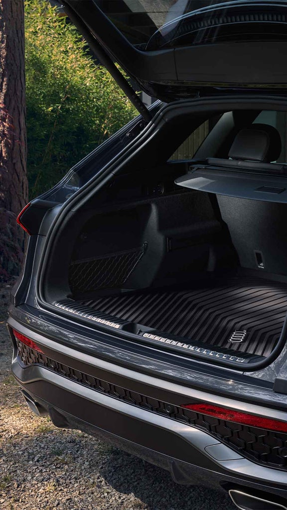 Geöffneter Kofferraum eines grauen Audi Q5 SUV mit geräumigem Innenraum im Waldumfeld.