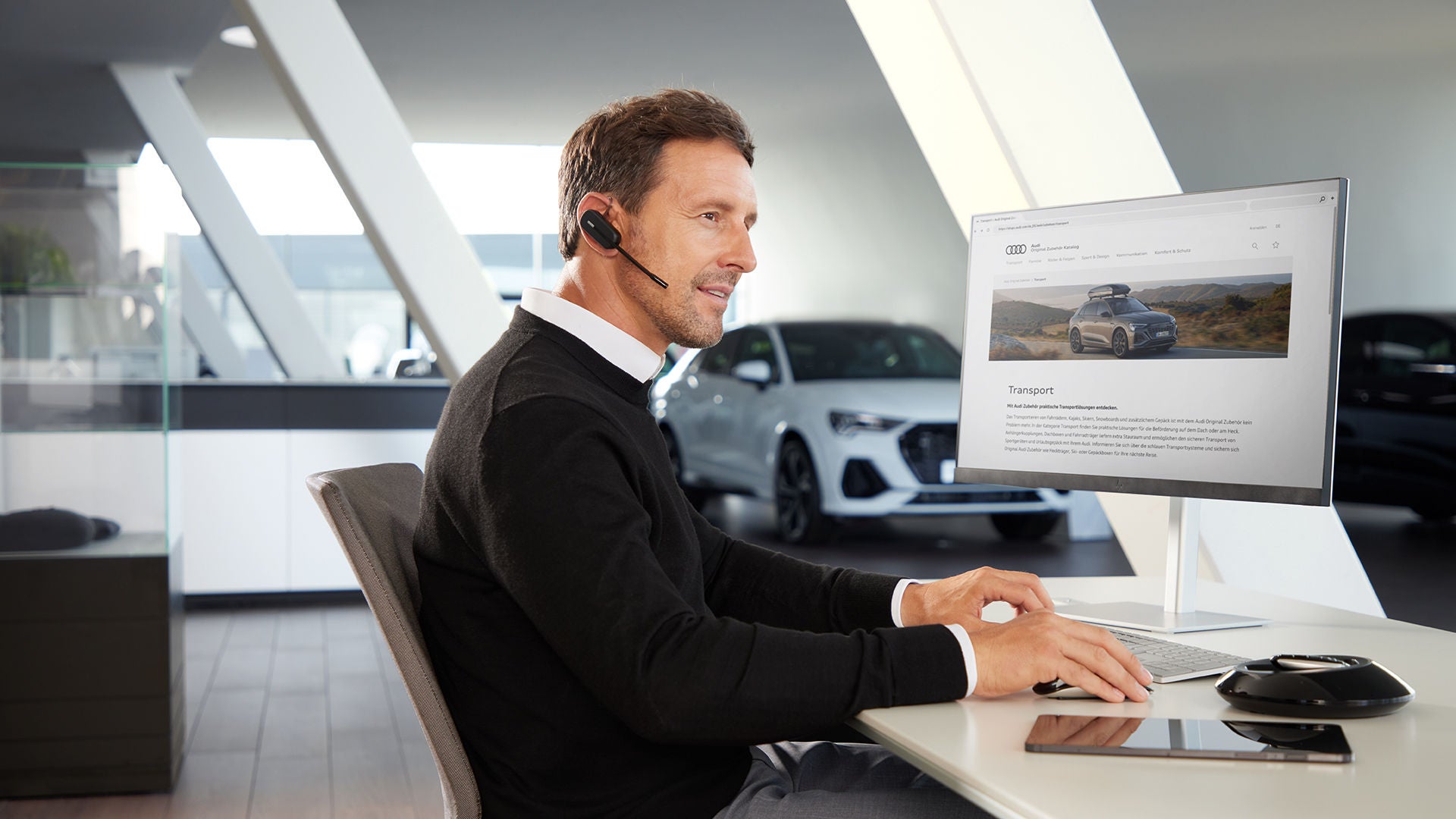 Ein Mann sitzt mit Headset an einem Computer