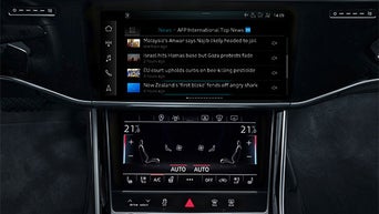 Zentraldisplay zeigt internationale Nachrichtenmeldungen, darunter eine digitale Klimaautomatik mit Sitzheizungssteuerung.