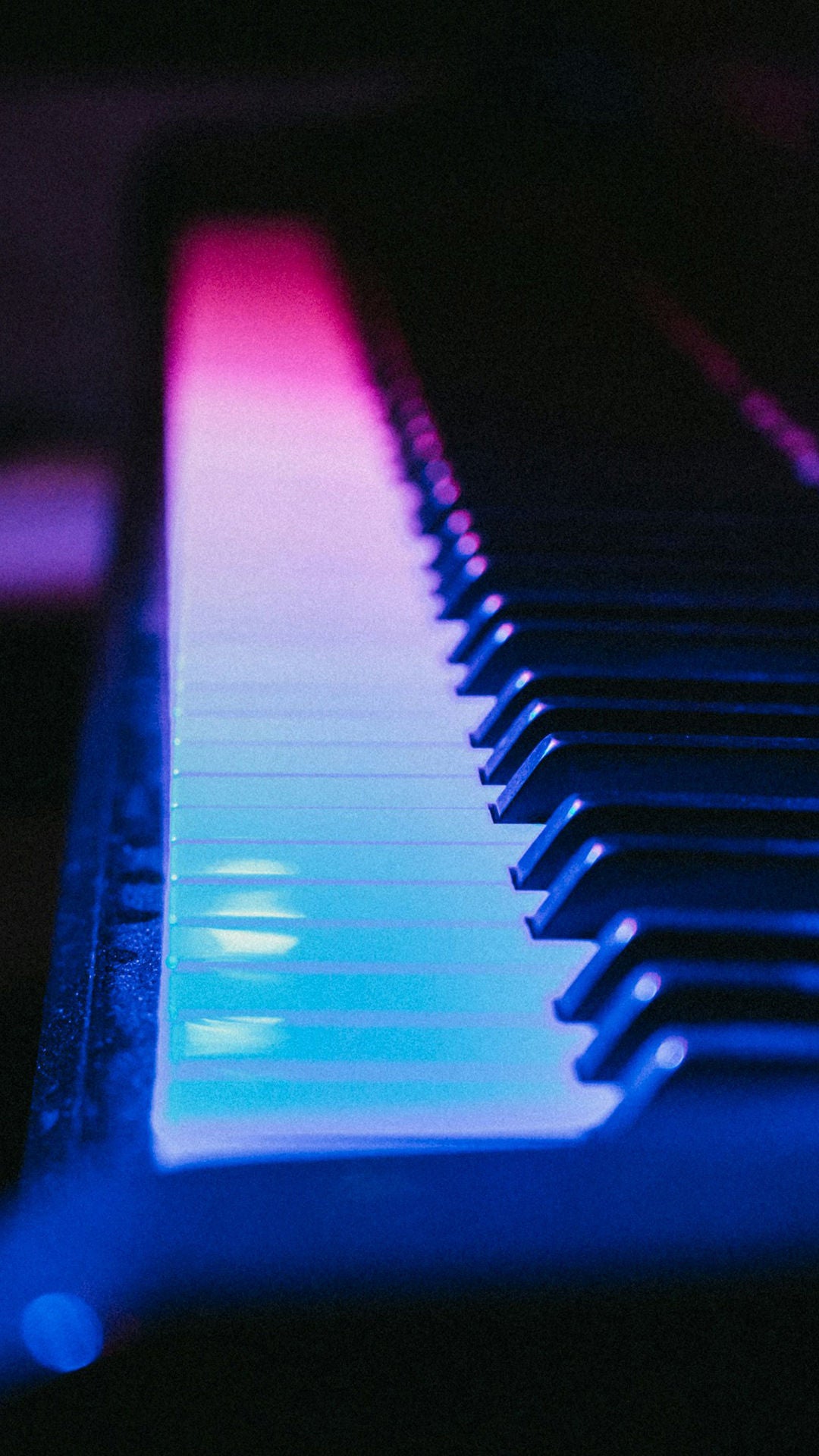 Nahaufnahme einer Klaviertastatur, von blau-rosa Licht angestrahlt, vor dunklem Hintergrund.