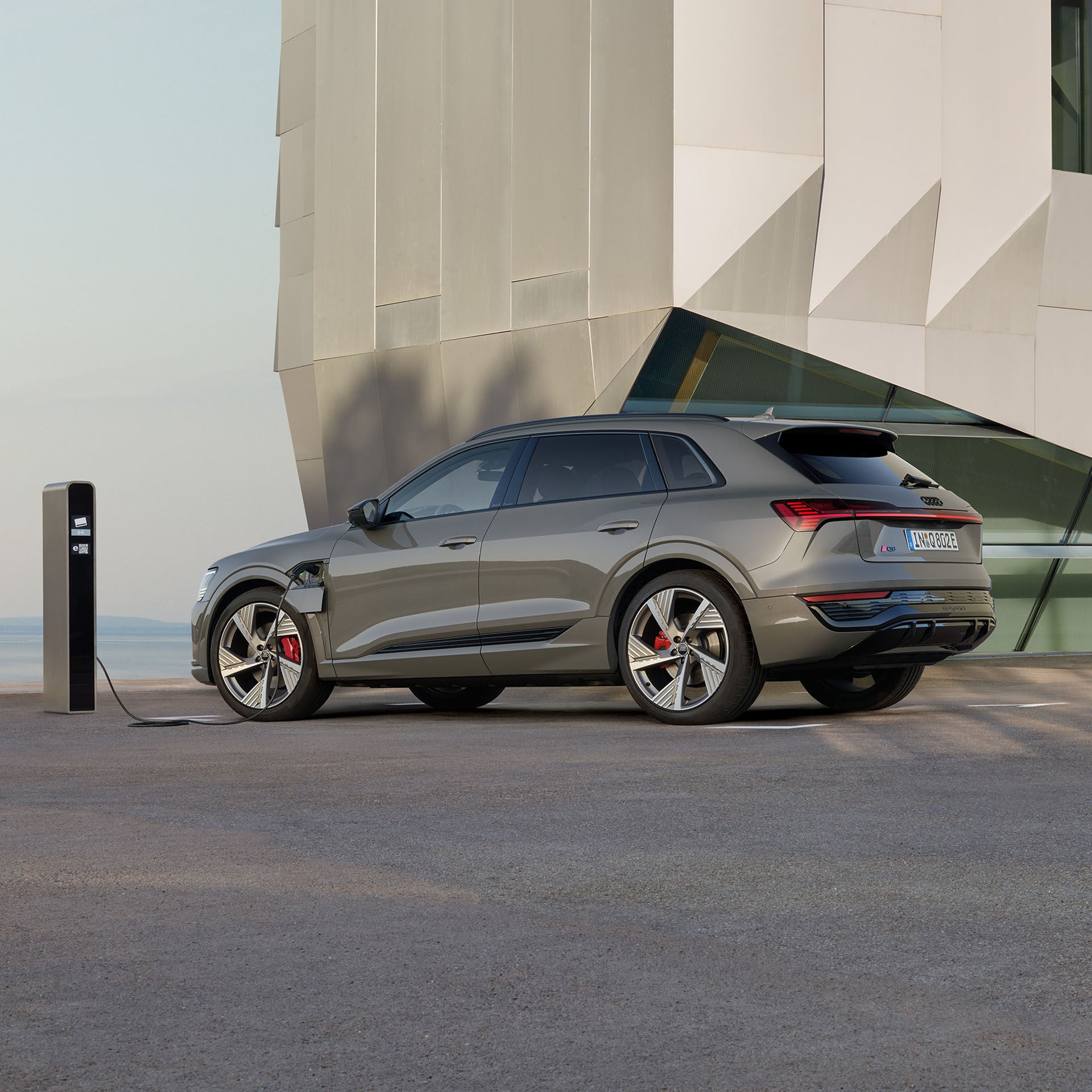 Q8 e-tron i profil som laddas vid en laddstolpe