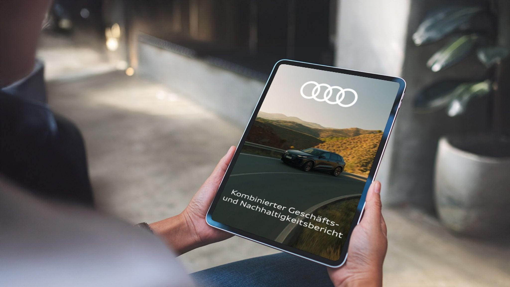 A woman holds a tablet with the words “Combined Annual and Sustainability Report” written on it.