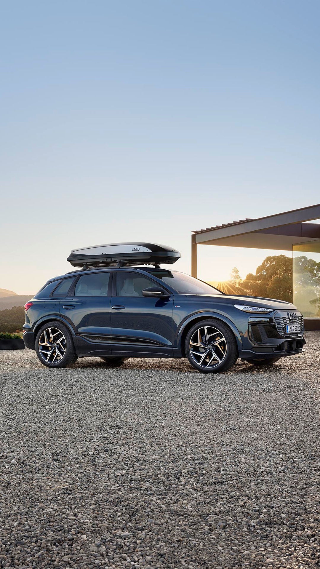 Audi steht links vor einem Haus und hat eine Dachbox aufgeschnallt