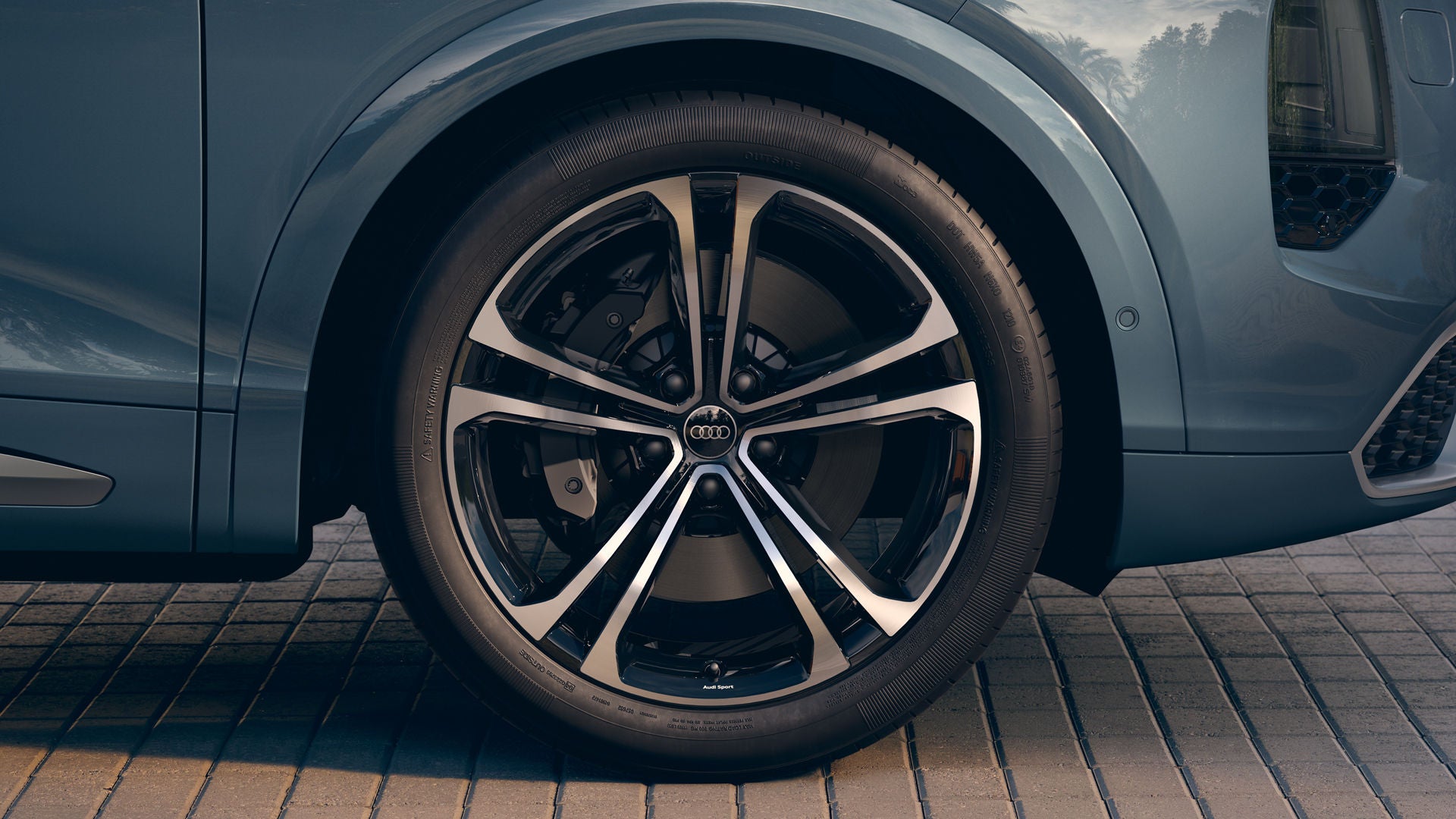 Gros plan sur une roue Audi équipée de jantes en alliage Audi Sport de 22 pouces au design S à rayons multiples, en noir métallisé.