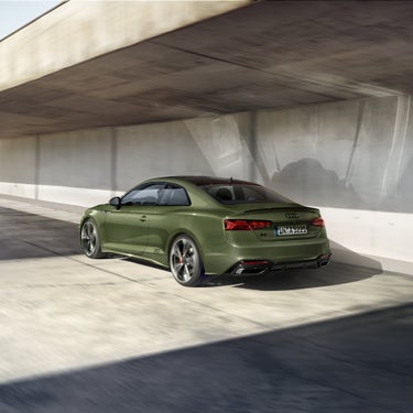 A green Audi A5 Coupe driving in a concrete underpass.