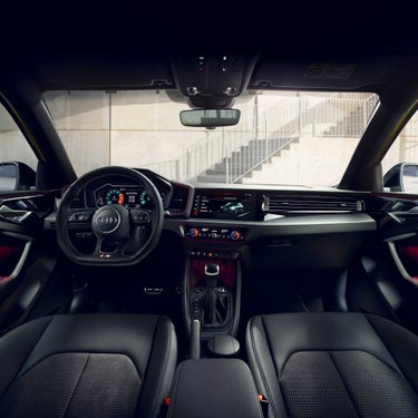 Interior view of Audi A1 Sportback car with steering wheel, dashboard, and seats, featuring modern design.