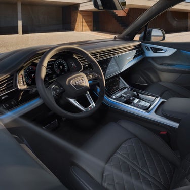 Interior view of a car with leather seats, steering wheel, and digital displays.