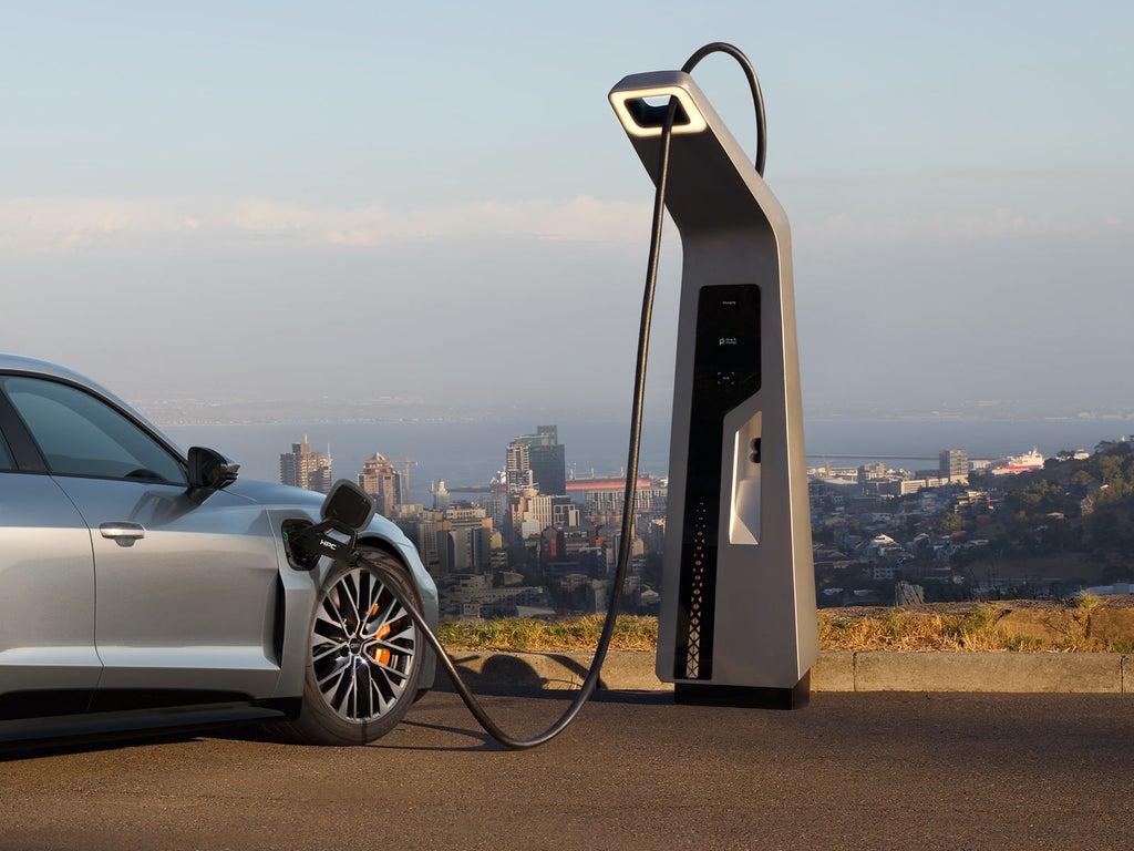 Ein silberner Audi S e-tron GT lädt an einer Ladestation mit Blick auf eine Stadt.